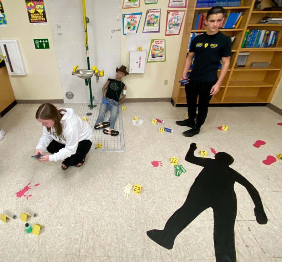 Seniors Kaitlynn Sayles and Tanner Bonneau examine the mock crime scene in Anglins classroom on Oct. 22. 